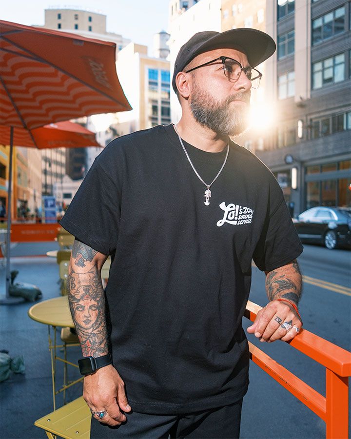 Artist LO on a city street corner with the sun shining from behind him